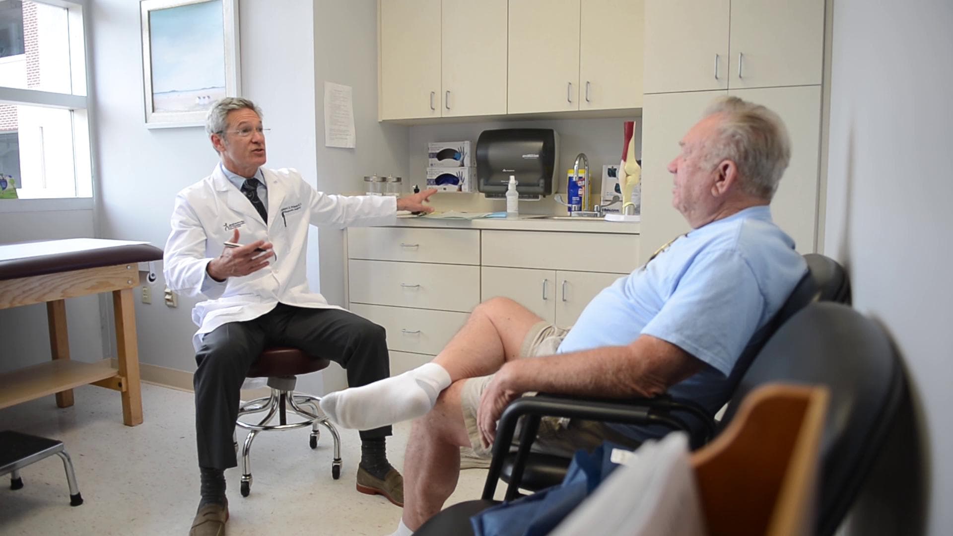Dr. Grimsley talking with a seated patient in an examination room