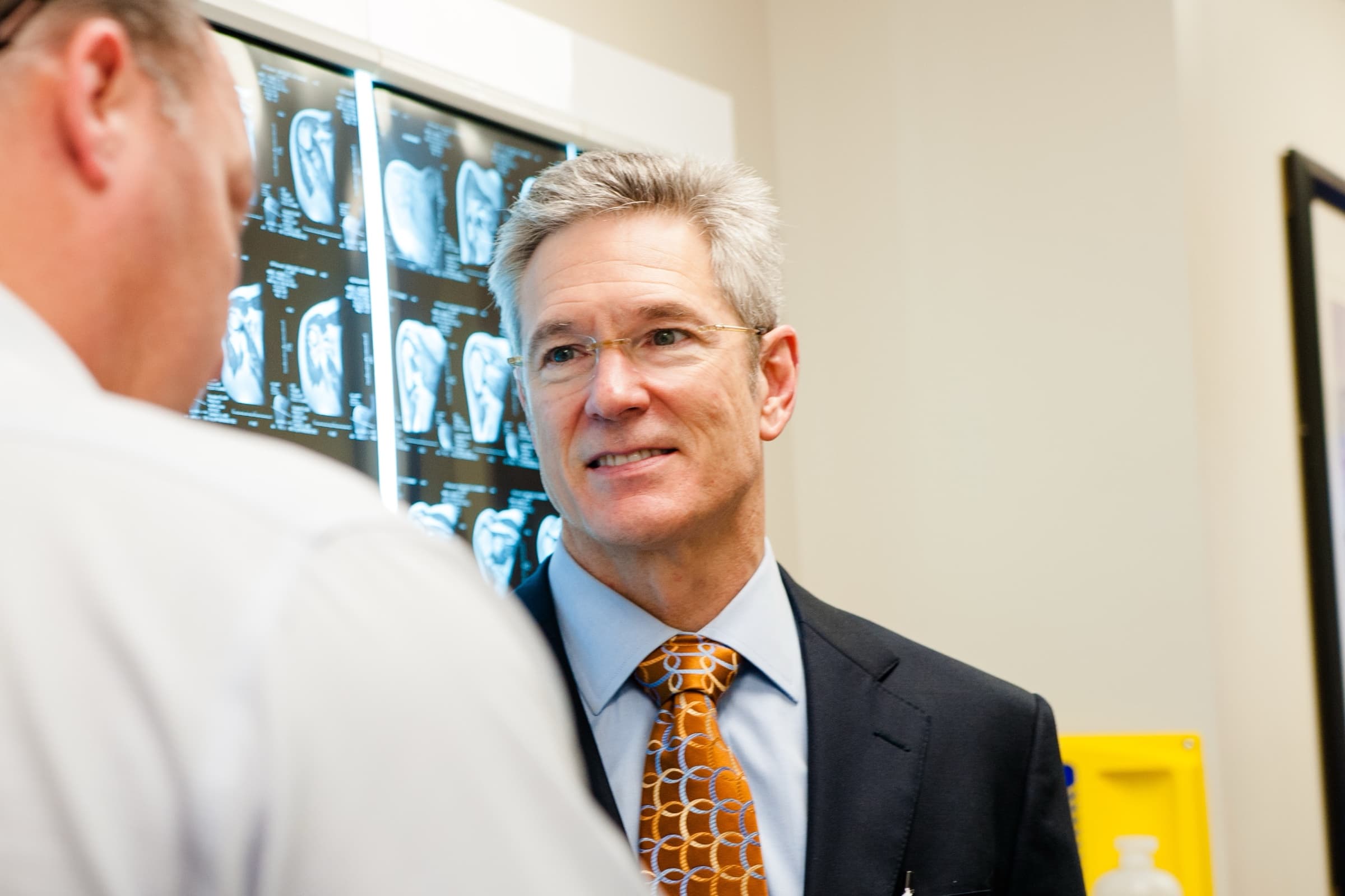 Dr. Grimsley talking with a patient in front of a lightbox of MRI scans